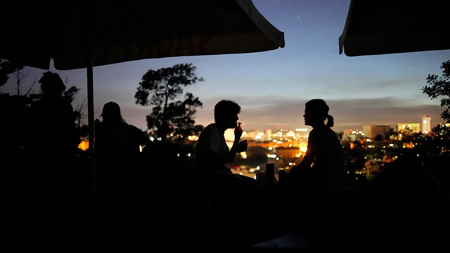 People sitting on the terrace of a closed bar at the Monte Agudo viewpoint, overlooking Lisbon, during a nationwide power cut on Monday 28 April.