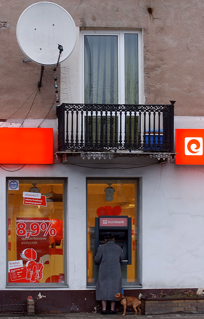 A woman draws money from an ATM in Warsaw, 14 December, 2006