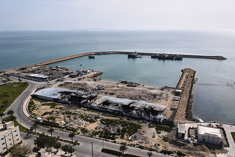 Backdropped by ships in the Strait of Hormuz damage caused by air seen on a pier in the port of Qeshm island, 13 April, 2026