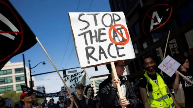 Varias personas marchan por San Francisco, EE. UU., portando pancartas contra la IA. Sonríen en un día soleado y un hombre lleva un chaleco reflectante.