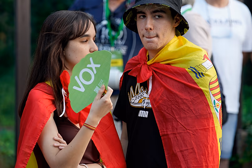 Supporters of far-right Vox party wearing Spanish flags over their shoulders stand outside the party headquarters in Madrid, 23 July, 2023