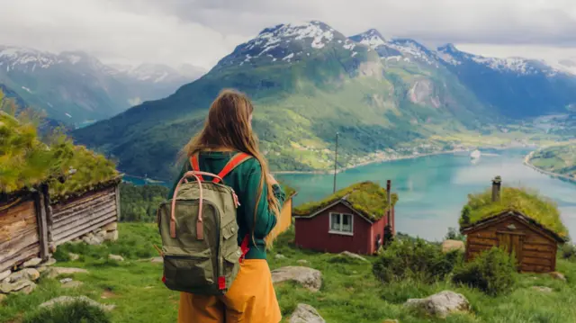 Vista de una mujer feliz contemplando los paisajes rurales veraniegos de Noruega