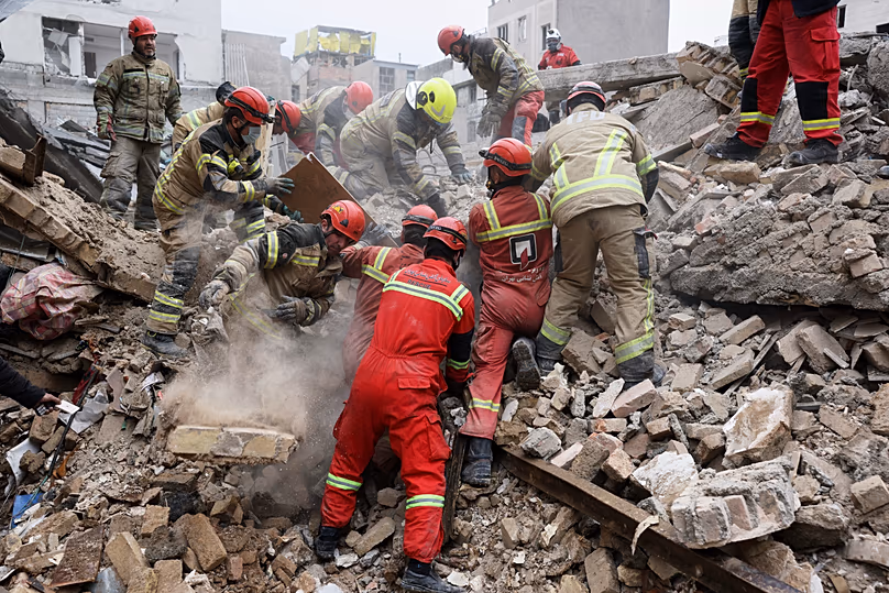 Rescue workers search for survivors in the rubble after a strike in southern Tehran, 13 March, 2026