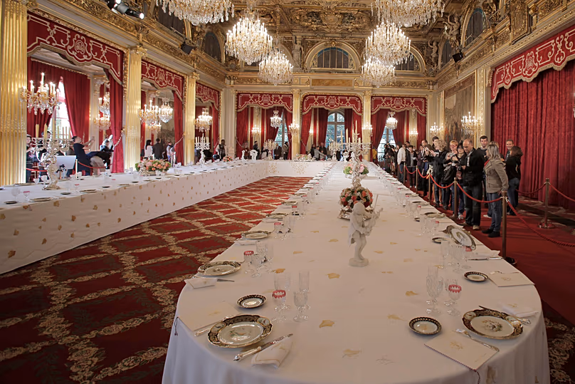 Visitors view a table dressed with plates and glasses for official dinners at the Élysée Palace in Paris, 15 September, 2012 