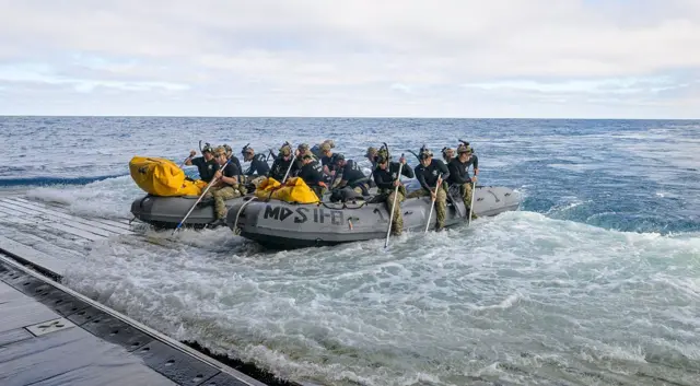Los buceadores de la Marina de EE. UU. se preparan para desplegarse en pequeñas embarcaciones desde la cubierta del USS John P. Murtha para recuperar a los tripulantes del Artemis II