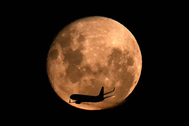 Avión pasando por delante a la Luna.