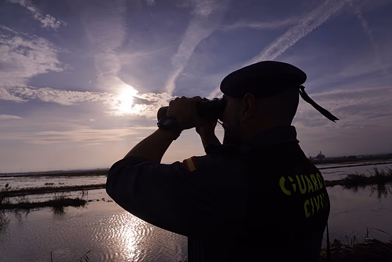 A Civil Guard officer looks though binoculars at the mouth of the Poyo ravine in the La Albufera natural lake near Puerto de Catarroja, 5 November, 2024