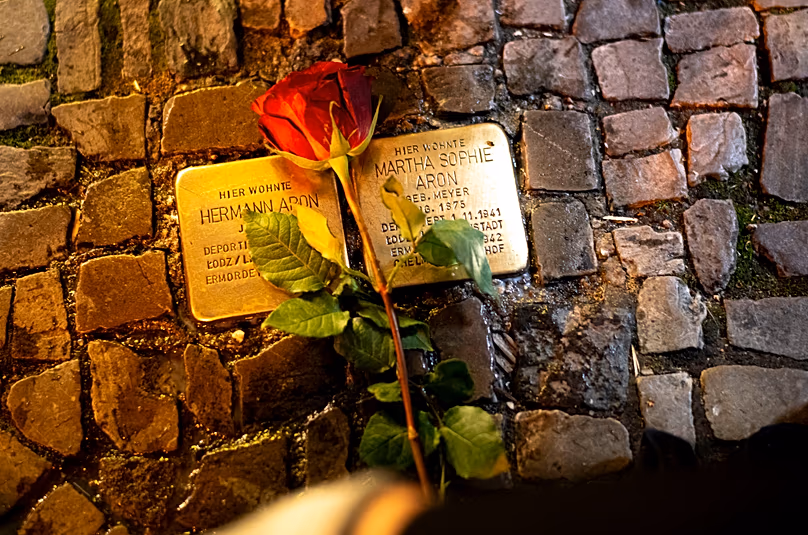 A rose is placed near a fresh polished so-called 'Stolpersteine' in Berlin, 8 November, 2023