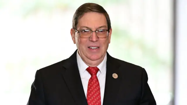 El ministro Bruno Rodríguez lleva puestos unos lentes y viste un traje oscuro, una camisa blanca y una corbata roja