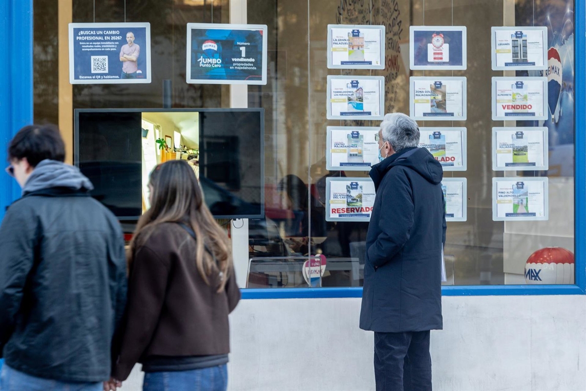 Un grupo de personas mira los anuncios de casas en venta en el escaparate de una inmobiliaria.