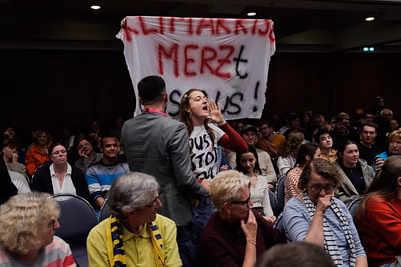 A young woman protests during a speech by Federal Chancellor Friedrich Merz at a panel discussion at the German Catholic Convention in Würzburg on 15 May 2026.