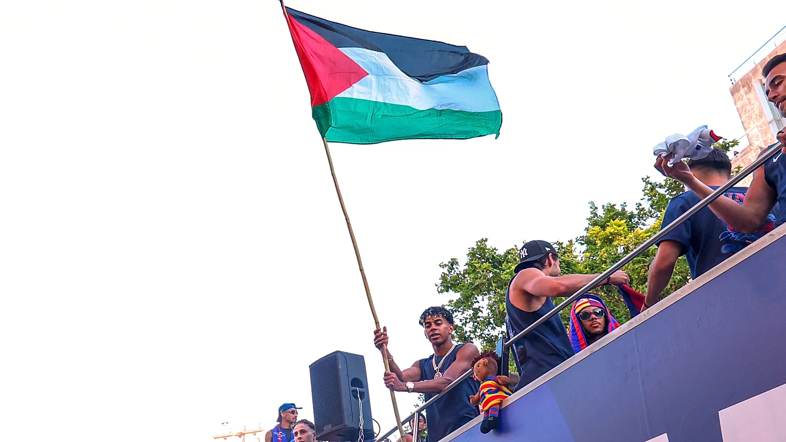 FC Barcelona player Lamine Yamal holds a Palestinian flag as he celebrates with his team atop a bus after winning the Spanish La Liga title in Barcelona, Spain, Monday, May 11