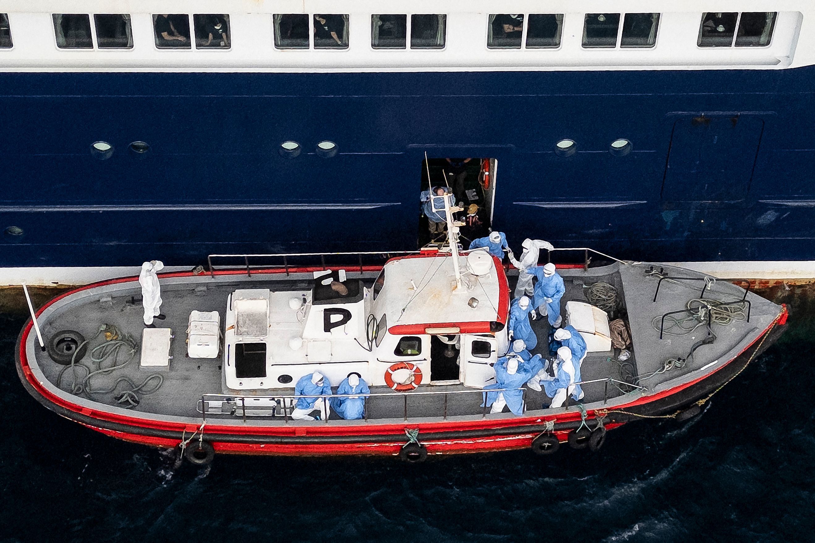 Personal sanitario ayuda a evacuar a las tres personas con síntomas que permanecían en el crucero anclado frente a Cabo Verde para ser trasladadas a Países Bajos.