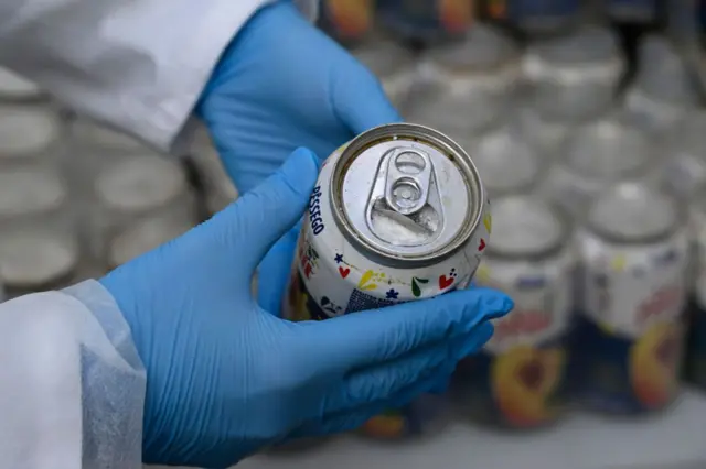 Un miembro de la Policía Judicial de Portugal muestra una lata de jugo de melocotón abierta e incautada que contenía cocaína, el 20 de mayo de 2024, en Lisboa, Portugal.