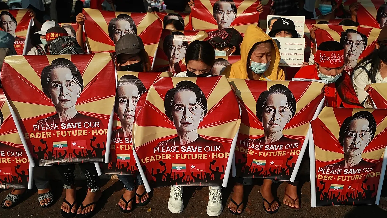 Anti-coup protesters hold posters with an image of Aung San Suu Kyi as they gather in Yangon, 20 February, 2021 
