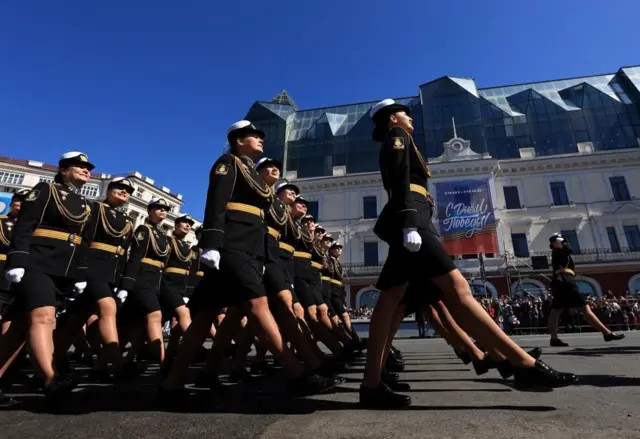 Militares rusas desfilan en filas por una calle de Vladivostok. El regimiento está formado por mujeres que visten uniformes negros y dorados.