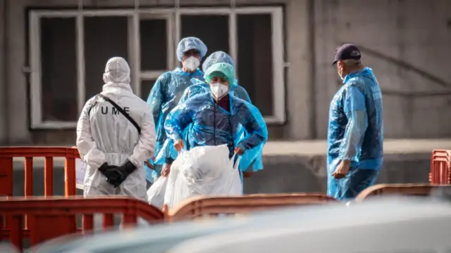 Pasajeros evacuados del crucero llevan mascarillas y protección en sus ropas para evitar contagios.