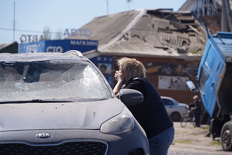 A woman cries as she looks at a dead driver inside a damaged car following a Russian missile attack in Merefa, 4 May, 2026