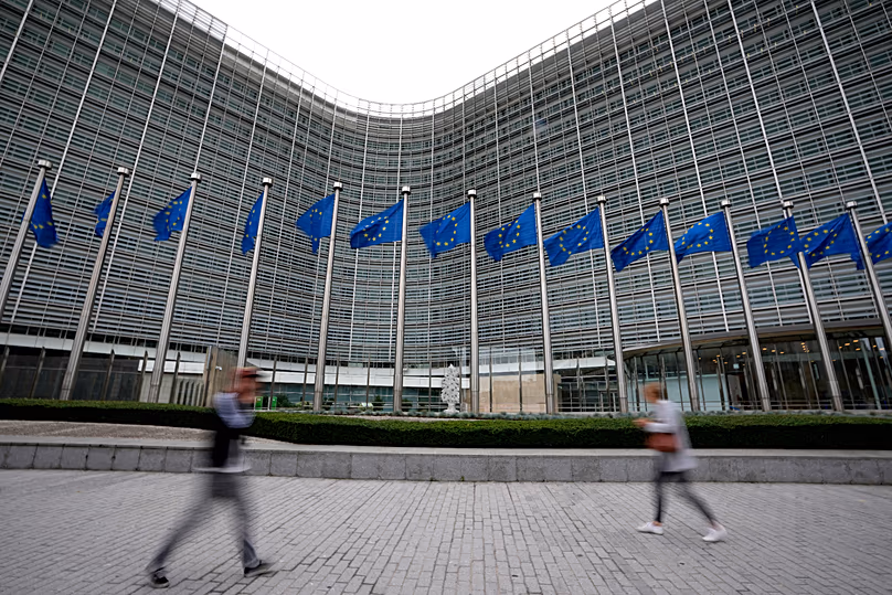 European Union flags flap in the wind as pedestrians walk by EU headquarters in Brussels, 20 September, 2023