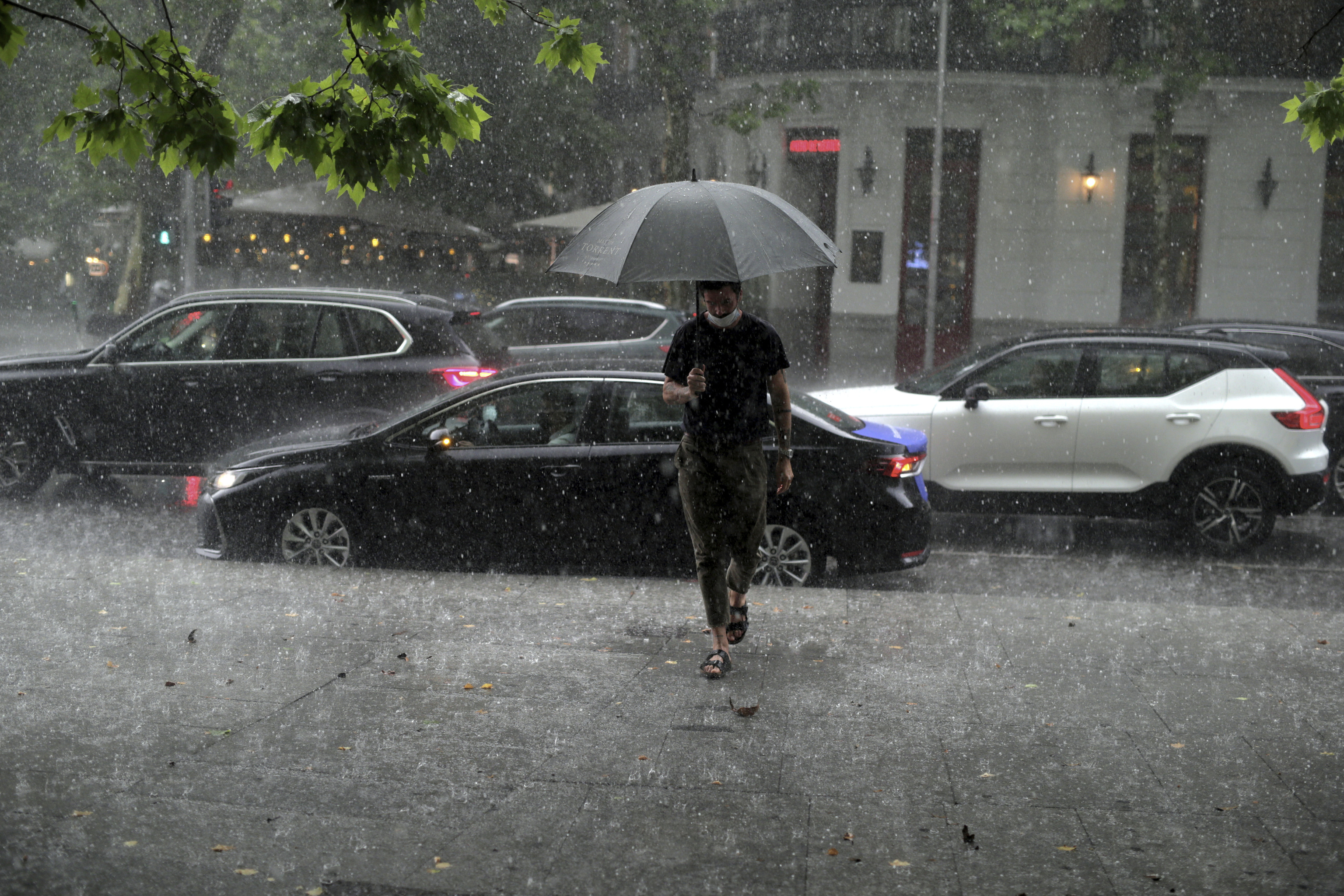 Un hombre pasea por una calle de Madrid bajo un intenso diluvio.