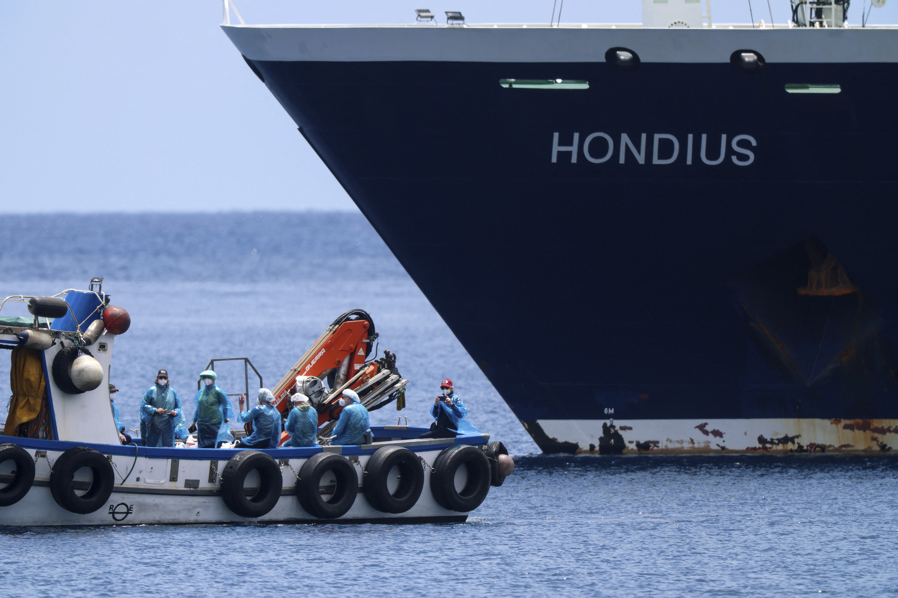 Varios pasajeros con sus trajes de protección abandonan el barco en la zódiac rumbo a tierra
