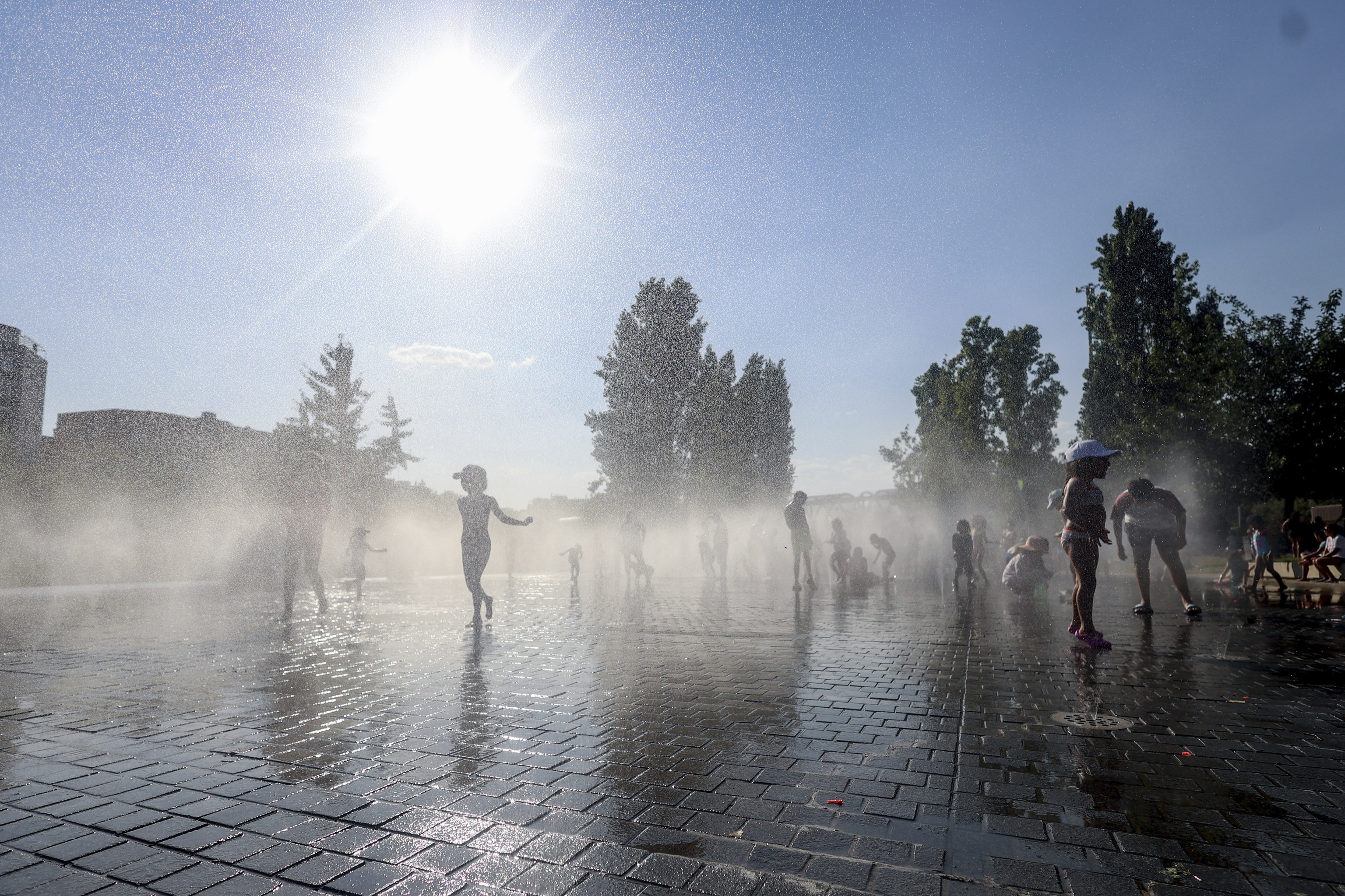 Varios niños juegan con fuentes de agua en un parque de Madrid.