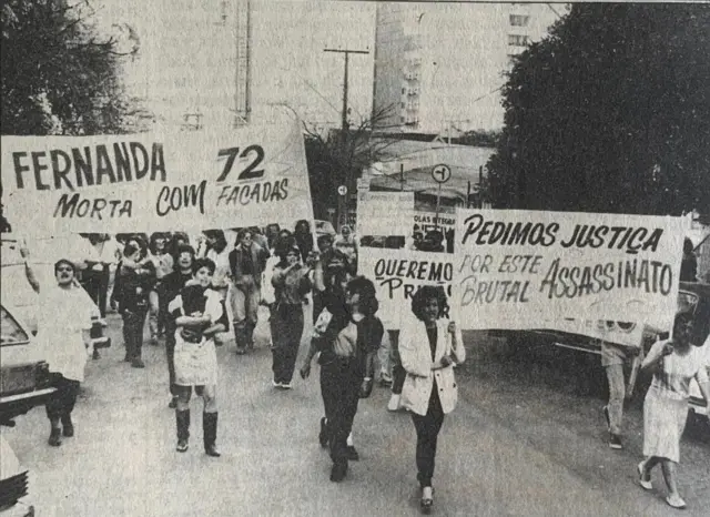 La foto muestra a personas con carteles y pancartas en la calle.