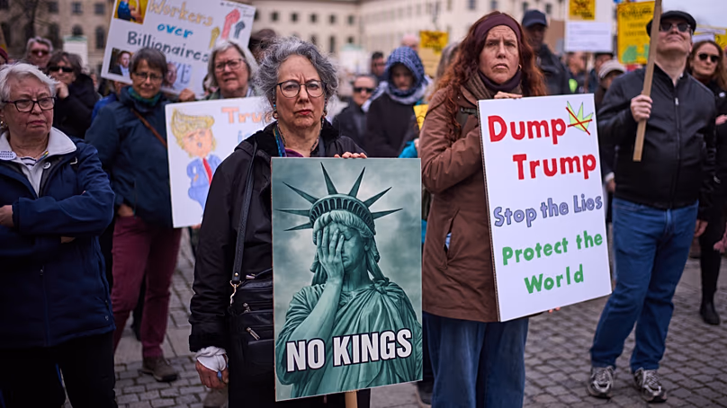 Demonstrators hold posters as they attend a No Kings Protest against the US government and President Donald Trump in Berlin, Germany, Saturday, March 28, 2026.