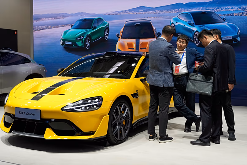 Visitors chat near a electric vehicle from Xiaomi displayed during the 2025 World Intelligent Connected Vehicles Conference in Beijing (AP Photo/Ng Han Guan) 
