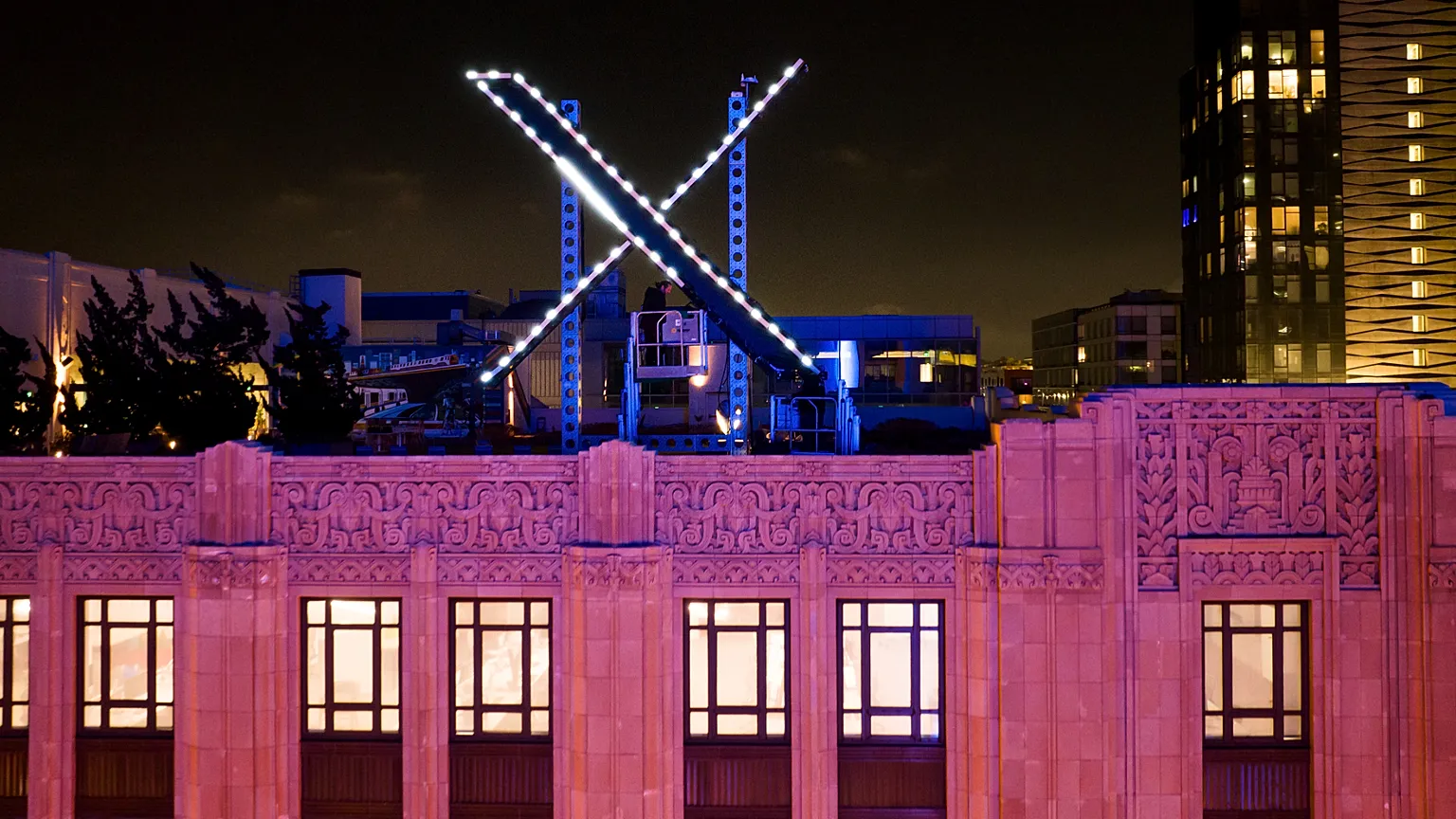 Workers install lighting on an "X" sign atop the company headquarters, formerly known as Twitter, in downtown San Francisco, Friday, July 28, 2023.