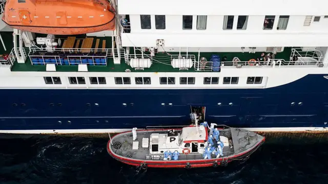 Personal médico asistiendo a pacientes para subir a un bote desde el crucero MV Hondius, anclado frente al puerto de Praia, capital de Cabo Verde, el 6 de mayo de 2026.