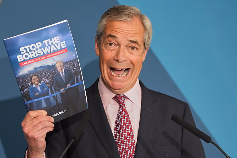 Nigel Farage leader of the Reform UK party holds up a booklet during a press conference in London, 13 April, 2026
