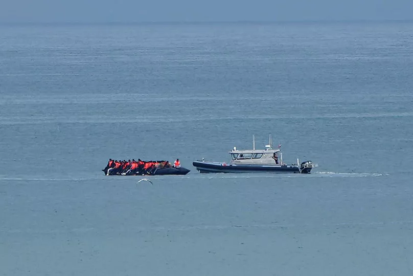 A boat thought to carry migrants is escorted by a vessel from the French Gendarmerie Nationale in the English Channel, 4 September, 2024