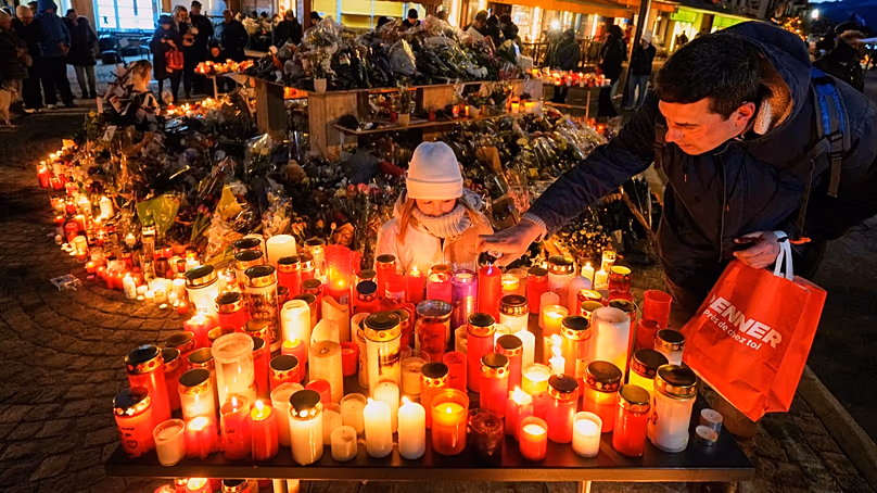 A child watches as an adult places a candle outside the sealed off Le Constellation bar in Crans-Montana (AP Photo/Baz Ratner, File)