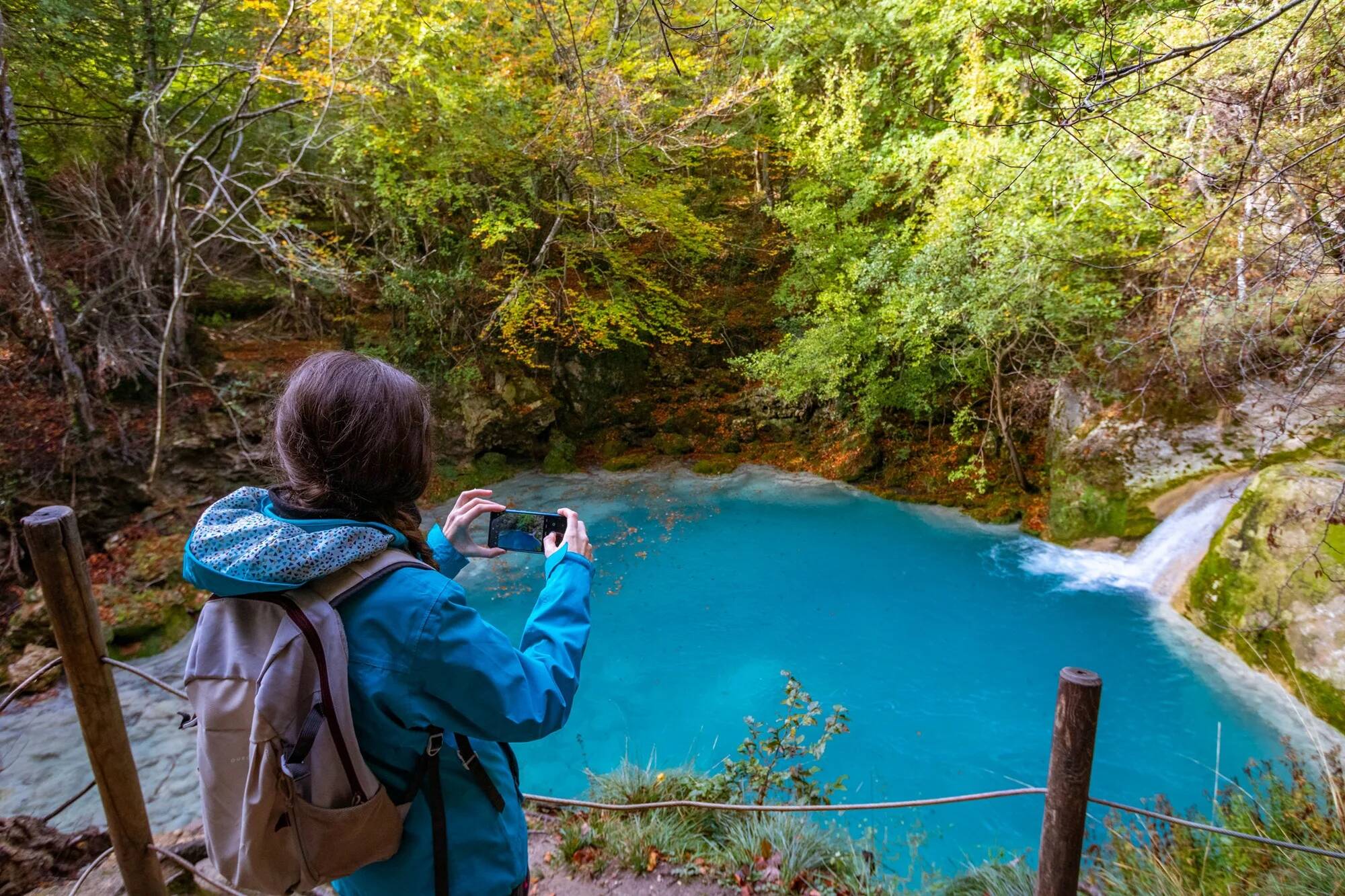 Foto: Una senderista fotografía una de las pozas turquesa de este rincón natural de Navarra. (Guía Repsol)
