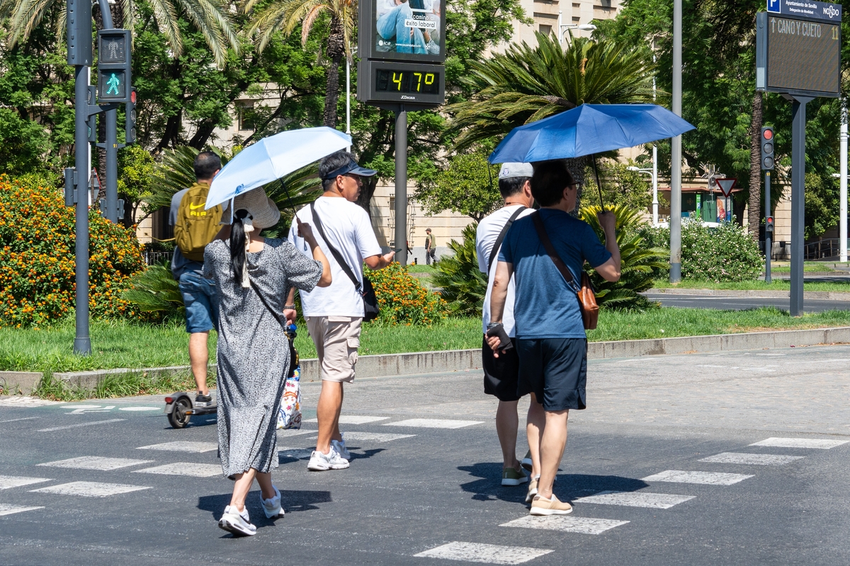 Personas al lado de un termómetro a 47 grados de temperatura, a 24 de julio de 2024, en Sevilla, Andalucía (España). (Francisco J. Olmo / Europa Press)