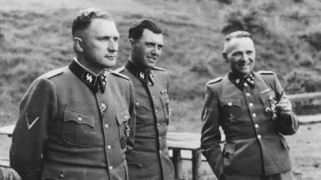 Tres hombres con uniforme de las SS nazis en una fotografía en blanco y negro.