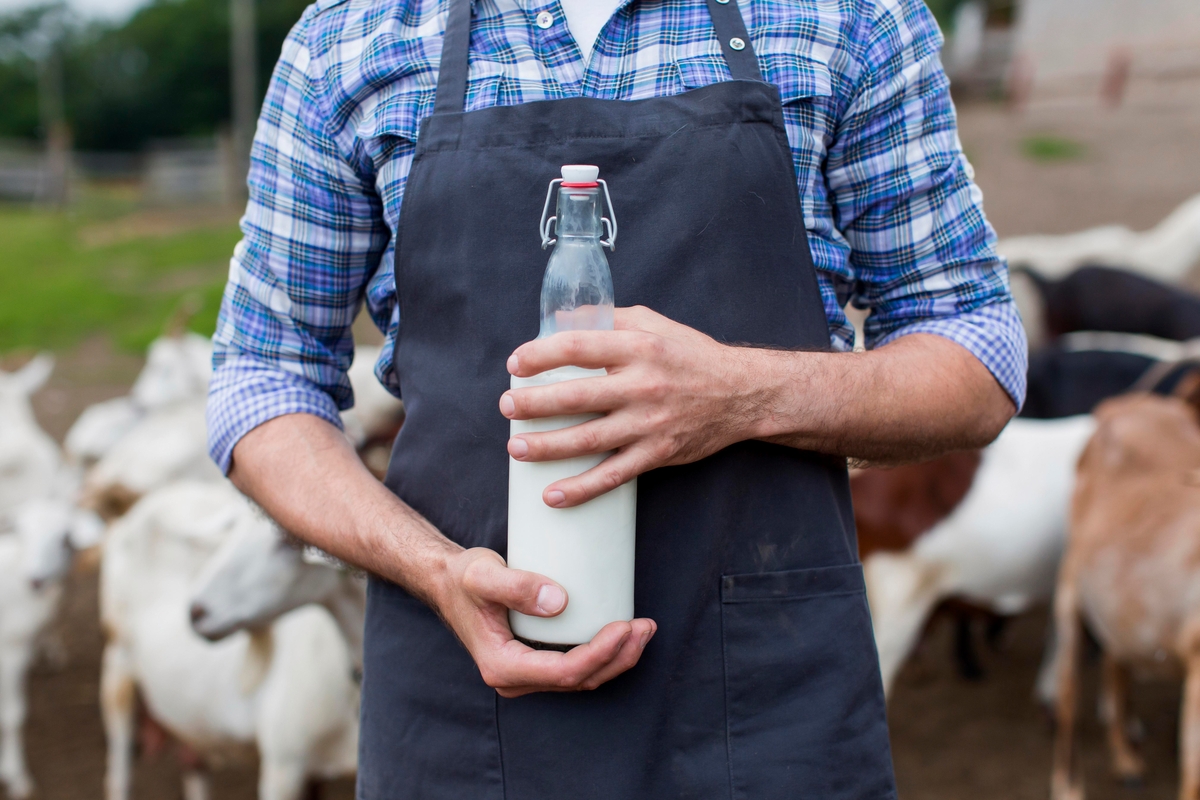 Un ganadero sosteniendo una botella de leche de cabra
