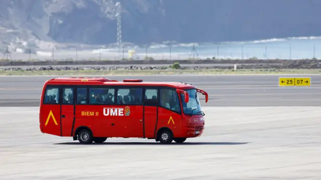 Un bus rojo traslada a pasajeros evacuados del crucero.