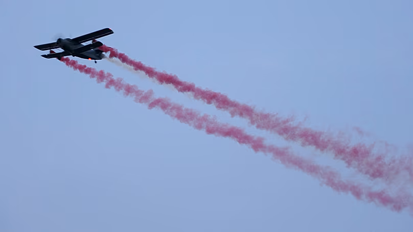 A vintage biplane paints the colors of the Latvian flag across the sky during a military parade on Latvian Independence Day, in Riga, 18 November, 2022.