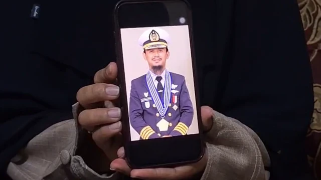 Santi Sanaya sostiene su teléfono, mostrando una foto de su esposo, el capitán Ashari Samadikun, quien fue tomado como rehén por piratas somalíes el 21 de abril de 2026.
