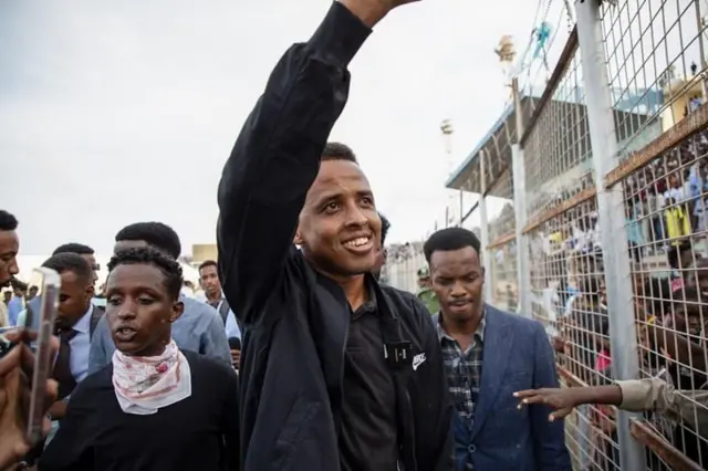 El árbitro somalí Omar Abdulkadir saluda rodeado de varios hombres al llegar de vuelta a Somalia