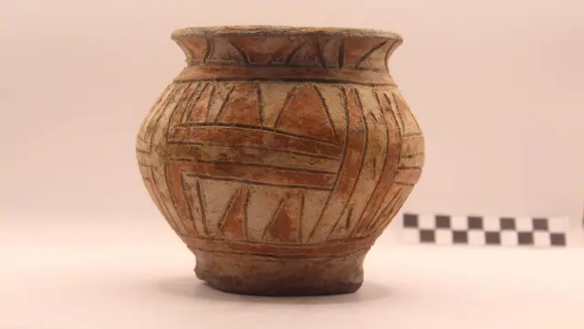 Vasija de cerámica con patrones geométricos sobre fondo neutro.
