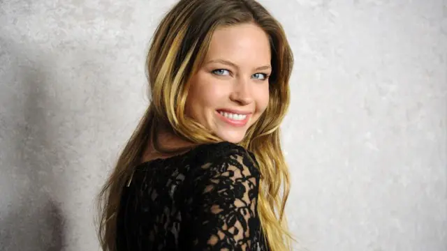 La actriz Daveigh Chase sonríe mientras mira por encima del hombro durante el estreno en 2011 de su serie de HBO, Big Love.