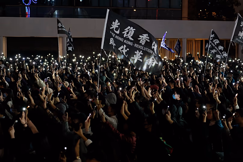 Manifestantes levantan las luces de sus teléfonos y sus manos para simbolizar las cinco demandas del movimiento prodemocrático en Hong Kong, 23 de diciembre de 2019