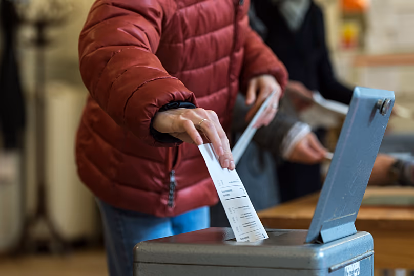 A Swiss voter casts a ballot in the ballot box at a voting centre in Bern, 30 November, 2014 