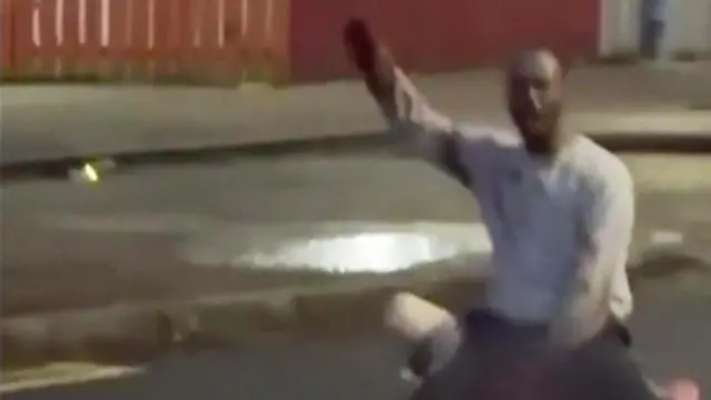 Imagen de un hombre con la mano en alto. Su rostro está borroso. 