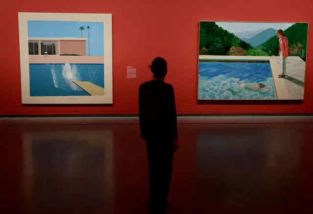 Una mujer observa dos de las pinturas más famosas del fallecido artista británico