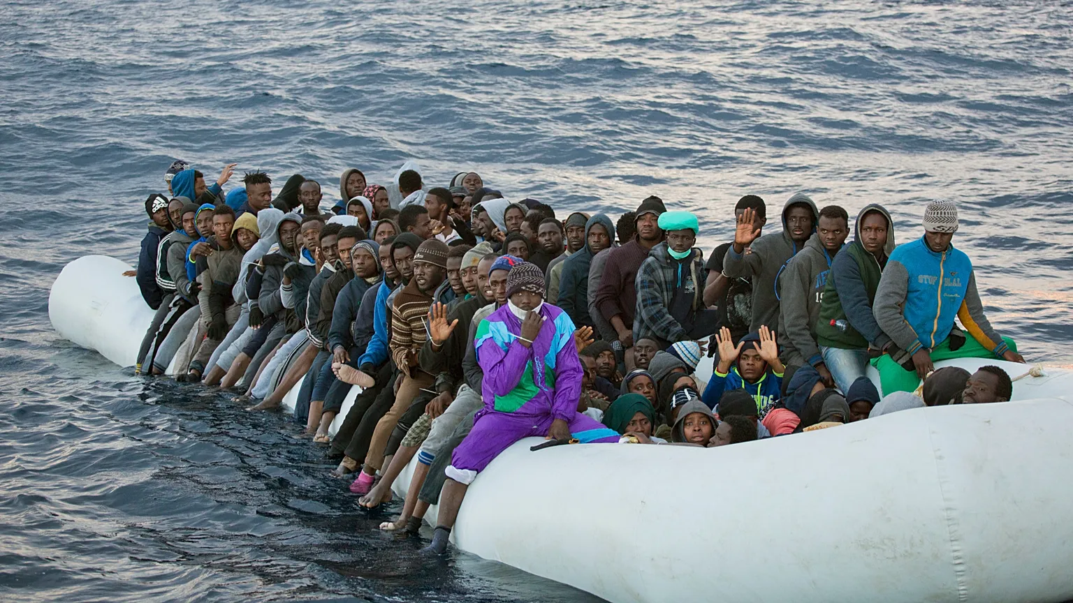 Migrants and refugees wait to be helped by members of the Spanish NGO Proactiva Open Arms, as they crowd aboard a rubber boat sailing out of control in the Mediterranean Sea a