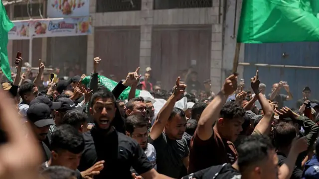 Los palestinos transportan los cuerpos de Imad Salim, también conocido como Abu Hassan, un alto mando del ala armada de Hamás, y de otras personas durante un cortejo fúnebre celebrado el mes pasado en la ciudad de Gaza. Los hombres vestidos de negro señalan al cielo, mientras que otros agitan banderas verdes.